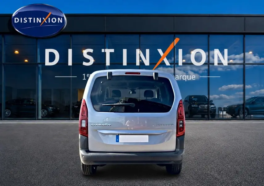 Vue arrière d'un Citroën Berlingo Steel Grey 2026 stationné devant une vitrine avec logo Distinxion.