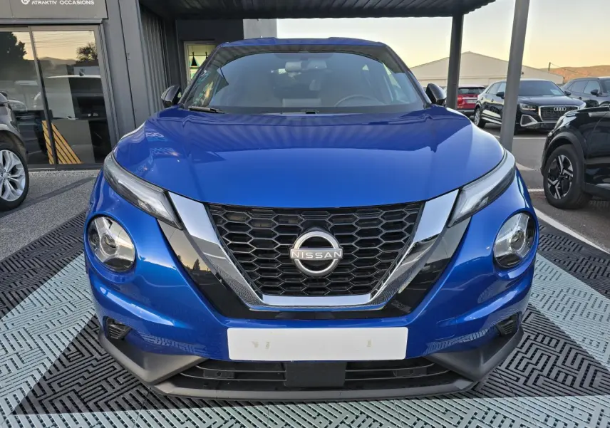 Vue frontale d'un Nissan Juke II bleu magnetic avec calandre en V chromée et phares LED distinctifs.