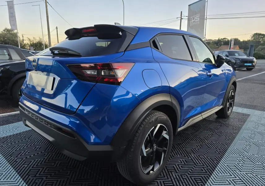 Vue 3/4 arrière droite d'un Nissan Juke II bleu magnetic avec jantes alliage noires et toit noir.