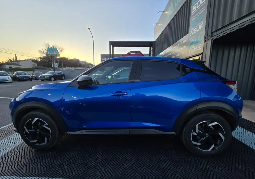 Profil côté gauche d'un Nissan Juke II bleu magnetic avec jantes alliage noires et vitres teintées.