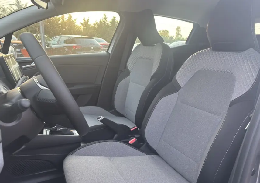 Vue intérieure côté gauche de la Renault Clio 2025 gris schiste, mettant en valeur les sièges tissu gris à motifs géométriques.