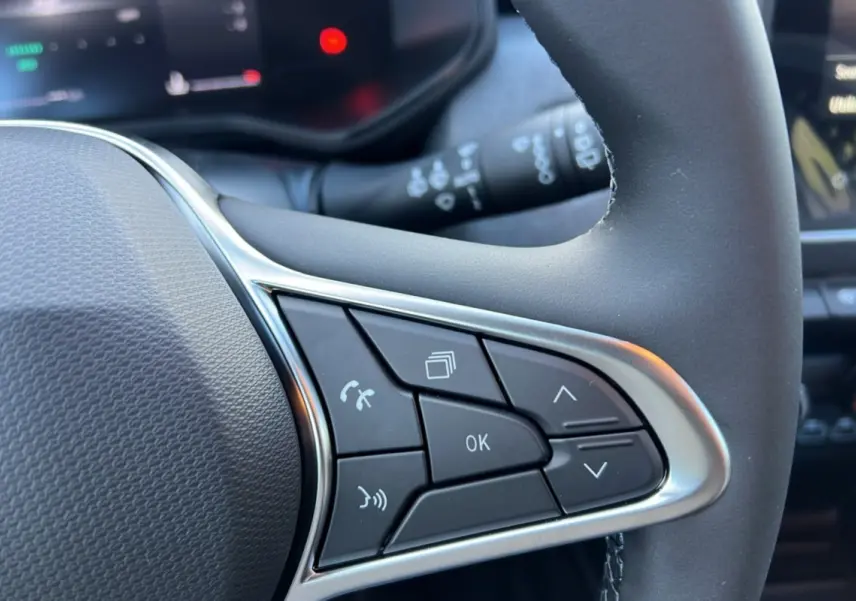 Gros plan sur les commandes multifonctions à gauche du volant de la Renault Clio 2025 gris schiste, version Evolution PK Look.