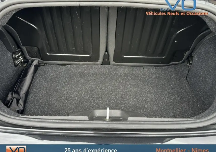 Coffre ouvert d'une FIAT 500C noire 2024, vue arrière montrant la roue de secours rangée sur le côté gauche.