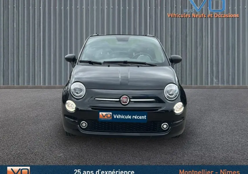Vue frontale d'une FIAT 500C noire 2024 avec phares allumés et toit ouvrant visible en arrière-plan.