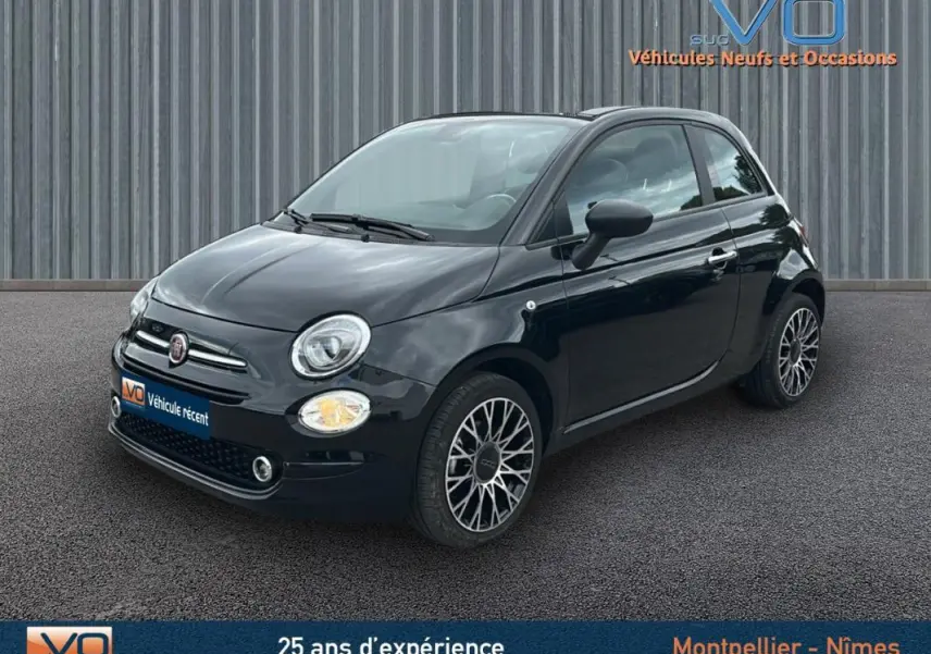 Vue 3/4 avant d'une FIAT 500C noire 2024 avec jantes alliage et toit rigide fermé sur fond urbain.