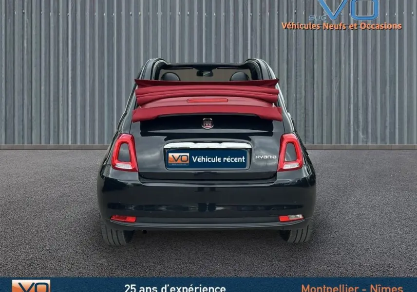 Vue arrière d'une FIAT 500C noire 2024 avec toit décapoté rouge et badge hybride visible sur le hayon.