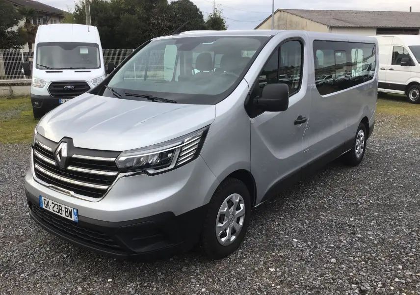 Vue 3/4 avant droite d’un Renault Trafic Combi gris Highland avec calandre chromée et vitres latérales teintées.