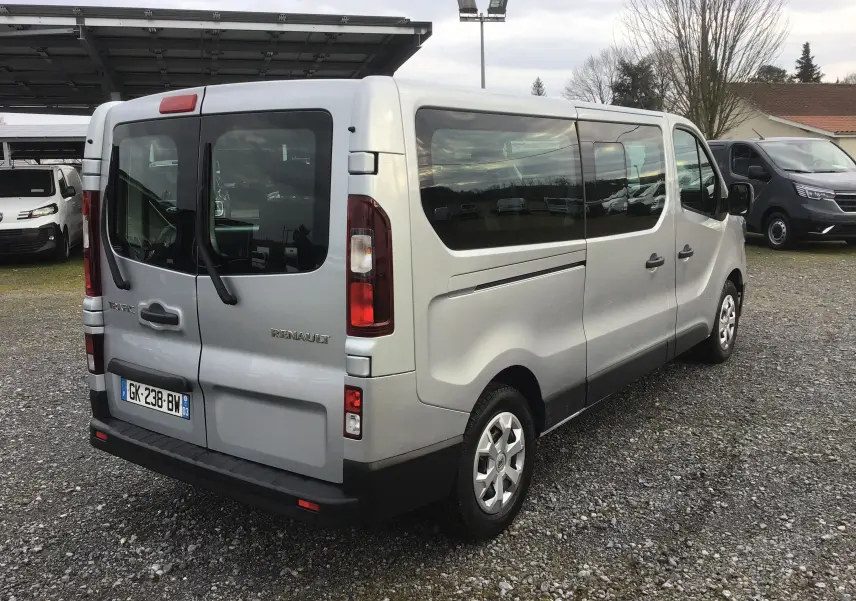 Vue 3/4 arrière droite d'un Renault Trafic Combi gris Highland, avec vitres latérales teintées et double porte arrière vitrée.