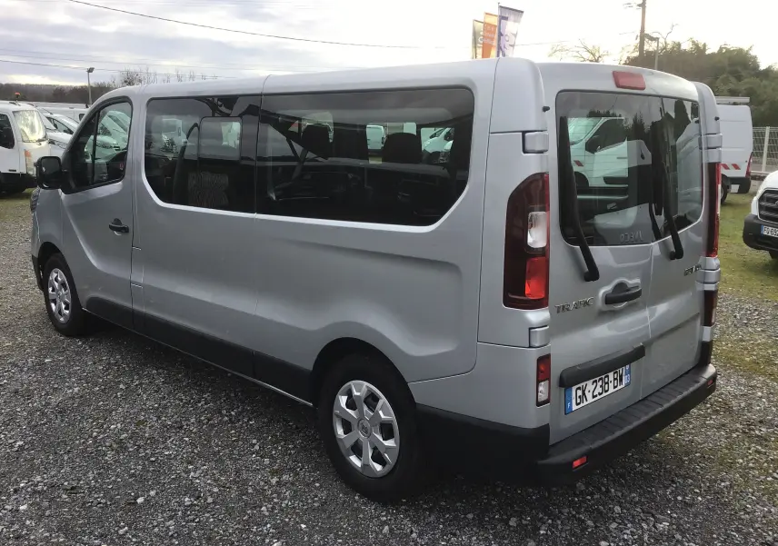 Renault Trafic Combi gris Highland vu en 3/4 arrière droit, avec vitres latérales teintées et porte arrière double.