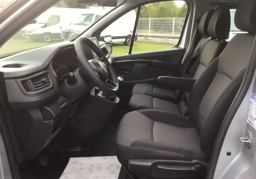 Vue intérieure côté conducteur du Renault Trafic Combi gris Highland 2022, montrant les sièges avant et le tableau de bord.