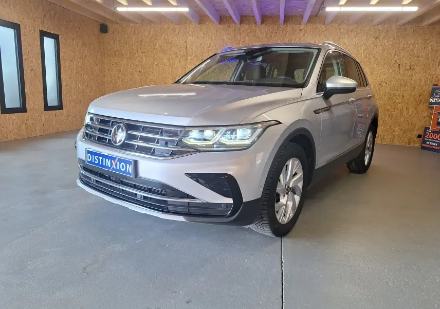 Volkswagen Tiguan gris métallisé vu de 3/4 avant droit avec jantes alliage 18 pouces et éclairage LED allumé.