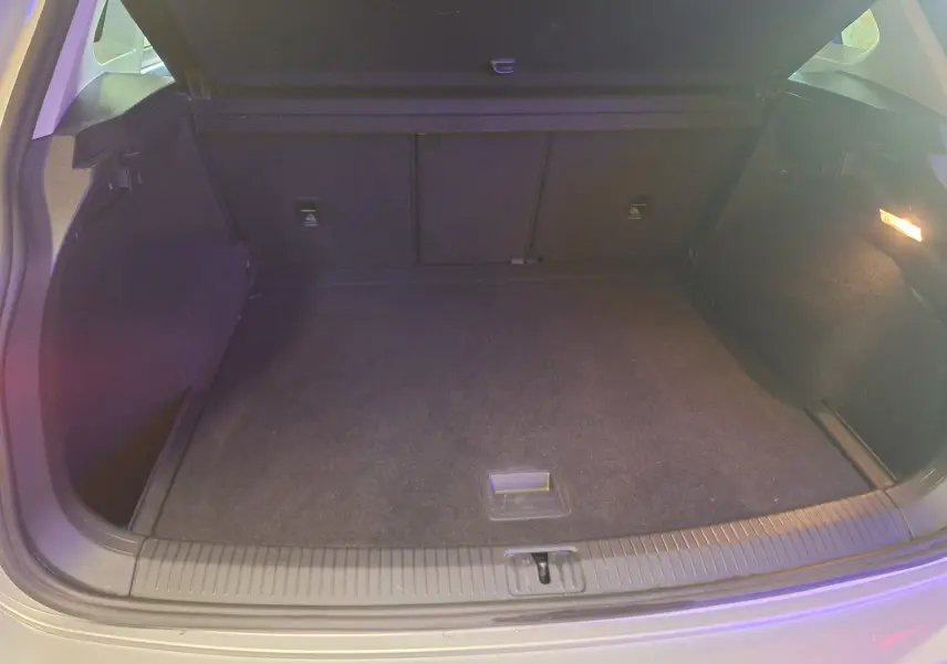 Coffre ouvert du Volkswagen Tiguan gris 2021, vue intérieure montrant un espace de chargement propre et éclairé.