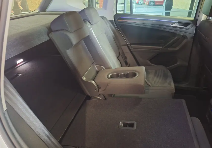 Vue intérieure arrière droite du Volkswagen Tiguan gris, avec accoudoir central relevé et siège rabattable.