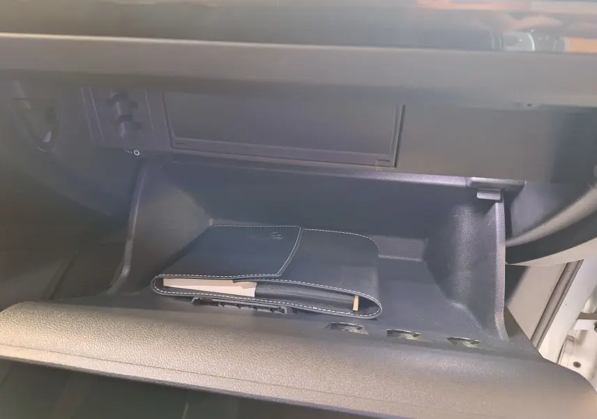 Vide-poche passager ouvert du Volkswagen Tiguan 2021 avec carnet d'entretien noir à l'intérieur