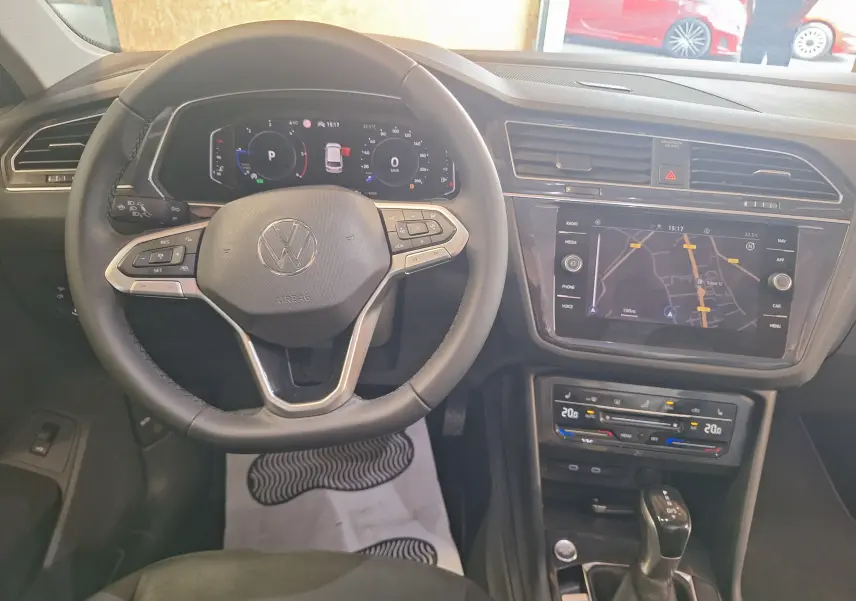 Vue intérieure du volant cuir multifonction et tableau de bord digital du Volkswagen Tiguan gris 2021 avec écran tactile central.