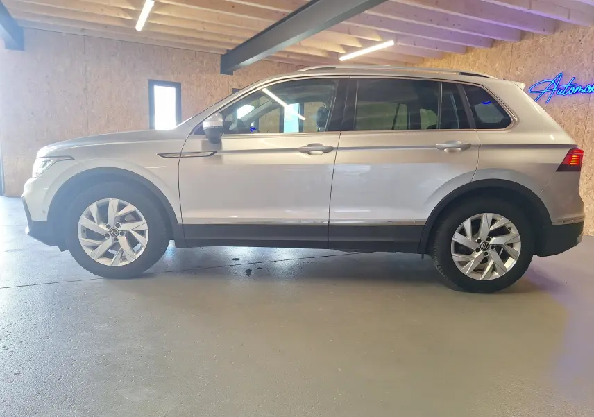 Profil côté gauche d'un Volkswagen Tiguan gris métallisé 2021 avec jantes alliage 18'' et jupes latérales chromées.