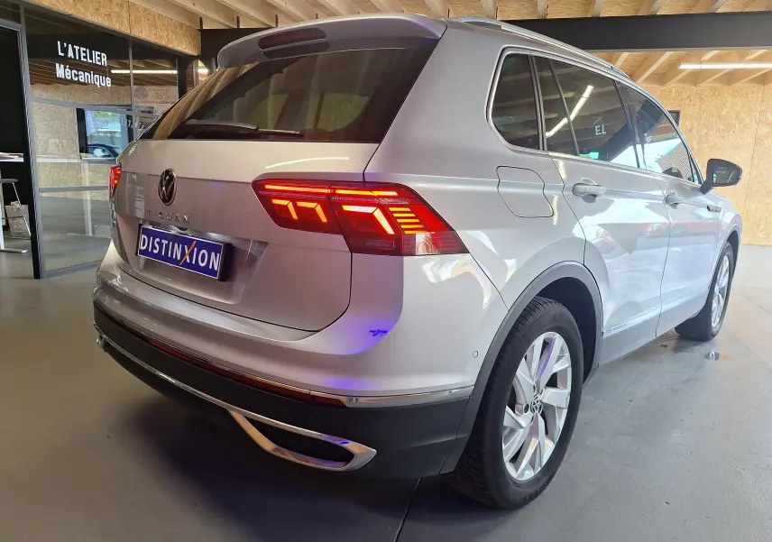 Vue 3/4 arrière droite du Volkswagen Tiguan gris métallisé avec feux LED allumés dans un garage.