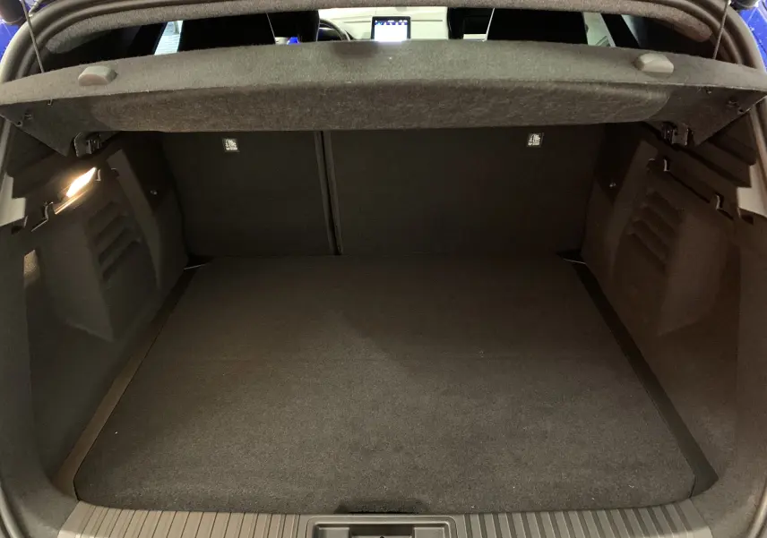 Coffre ouvert vu de l'arrière d'une Renault SYMBIOZ bleu Iron, montrant un espace de chargement propre et spacieux.