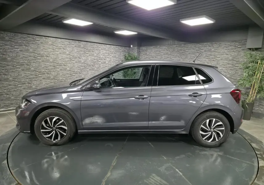 Volkswagen Polo gris métallisé vue de profil côté gauche avec jantes alliage et vitres arrière surteintées.