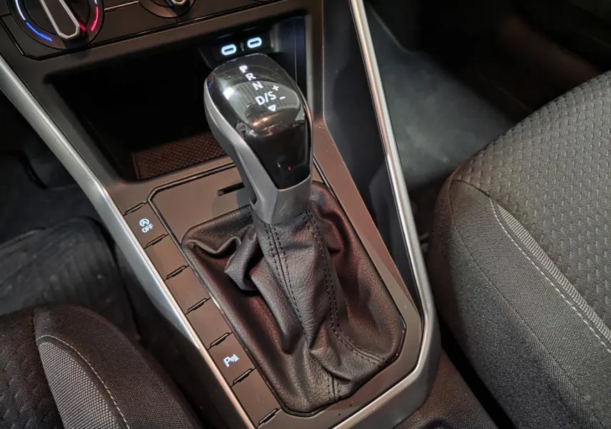 Gros plan sur levier de vitesses automatique noir et console centrale grise dans Volkswagen Polo gris 2025.