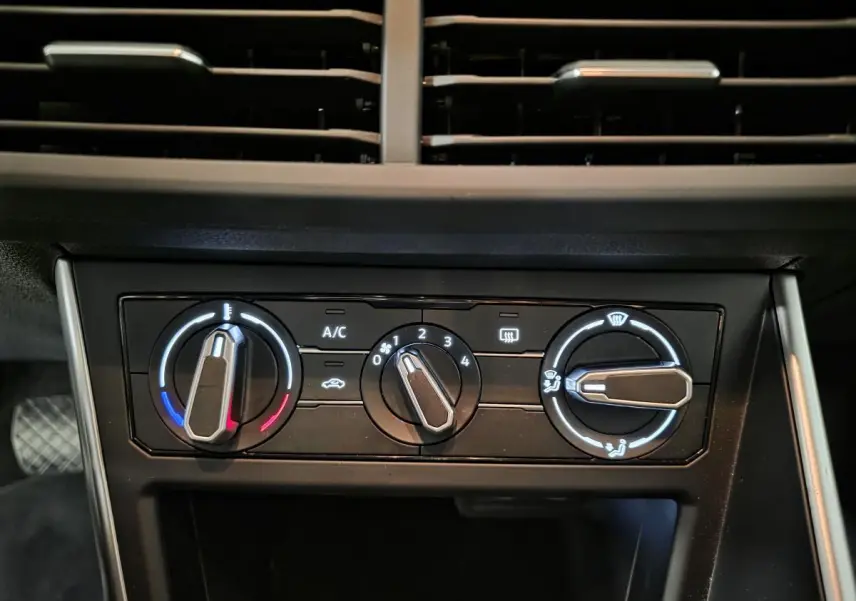 Vue rapprochée des commandes de climatisation manuelle sur le tableau de bord noir du Volkswagen Polo gris 2025.