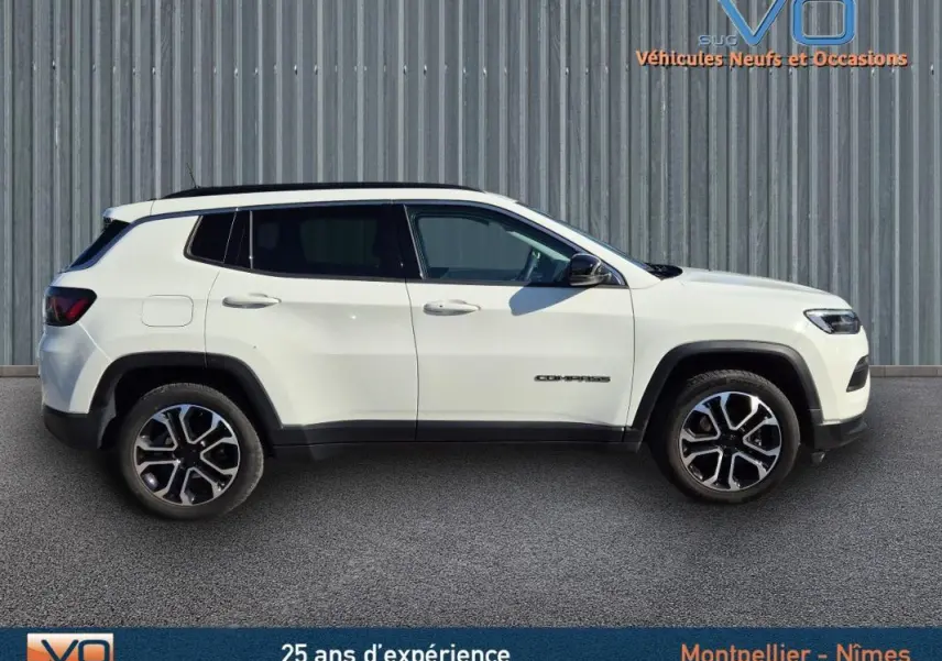 Profil côté gauche d'un Jeep Compass blanc 2023 avec jantes 18 pouces et barres de toit visibles.