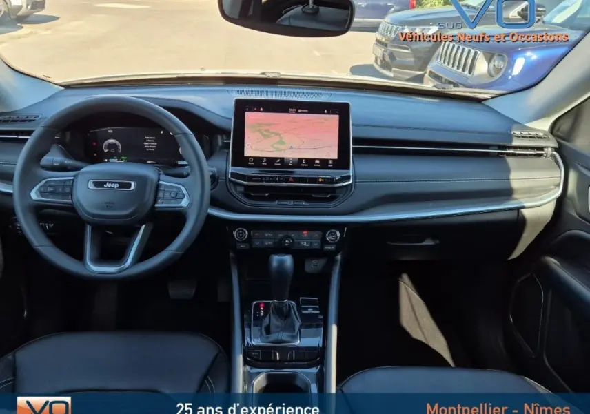 Intérieur du Jeep Compass 2023 vu de face, tableau de bord noir avec écran tactile central et volant multifonction.
