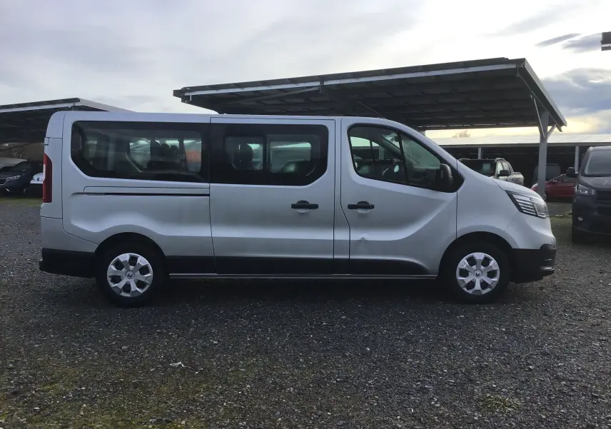 Profil côté gauche d'un Renault Trafic Combi gris clair métal 2023, véhicule utilitaire spacieux avec vitres teintées.