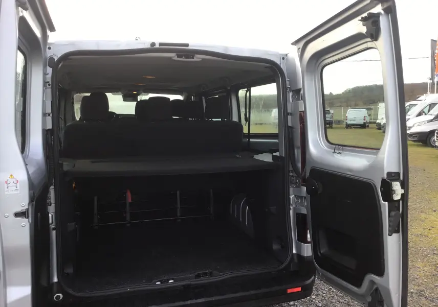 Vue arrière ouverte du Renault Trafic Combi gris clair métal 2023, montrant l'espace de chargement et les sièges arrière.