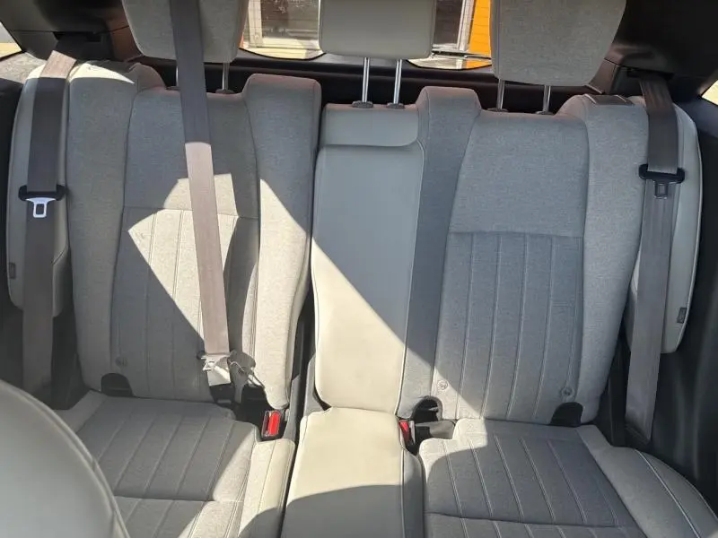 Vue intérieure de la banquette arrière gris clair de la Honda Jazz 1.5 i-MMD avec ceintures de sécurité visibles.