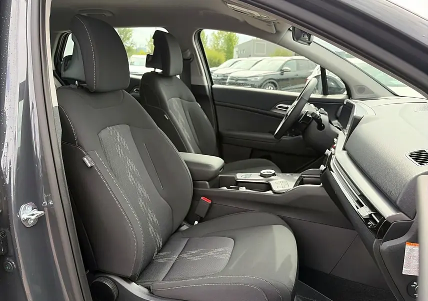 Vue intérieure côté conducteur du Kia Sportage 1.6 hybride 239 gris eclipse, avec sièges noirs et console centrale moderne.