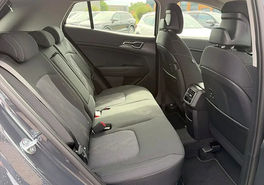 Vue intérieure côté droit montrant la banquette arrière grise du Kia Sportage 1.6 hybride 239 active 2026 avec appuie-têtes et aérateurs centraux.
