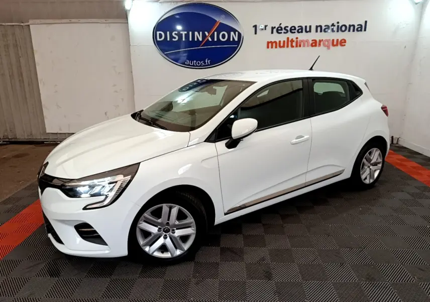 Renault Clio Business blanche vue de côté droit en intérieur, avec feux avant allumés et jantes alliage.