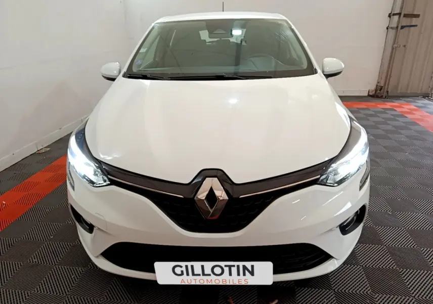 Vue avant d'une Renault Clio Business blanche avec phares LED allumés dans un garage intérieur.