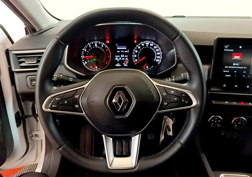 Vue intérieure centrée sur le volant cuir noir de la Renault Clio Business blanc, avec tableau de bord et écran tactile visibles.