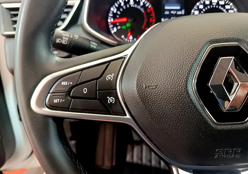 Gros plan sur le volant cuir noir de la Renault Clio Business 2021 avec commandes de régulateur de vitesse et logo central.