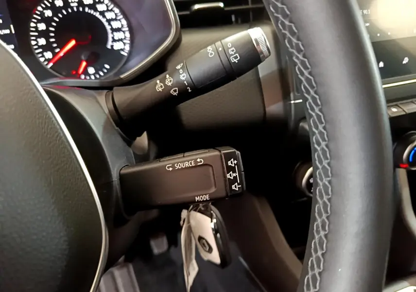 Gros plan sur le volant noir et la commande multifonction de la Renault Clio Business blanche de 2021.