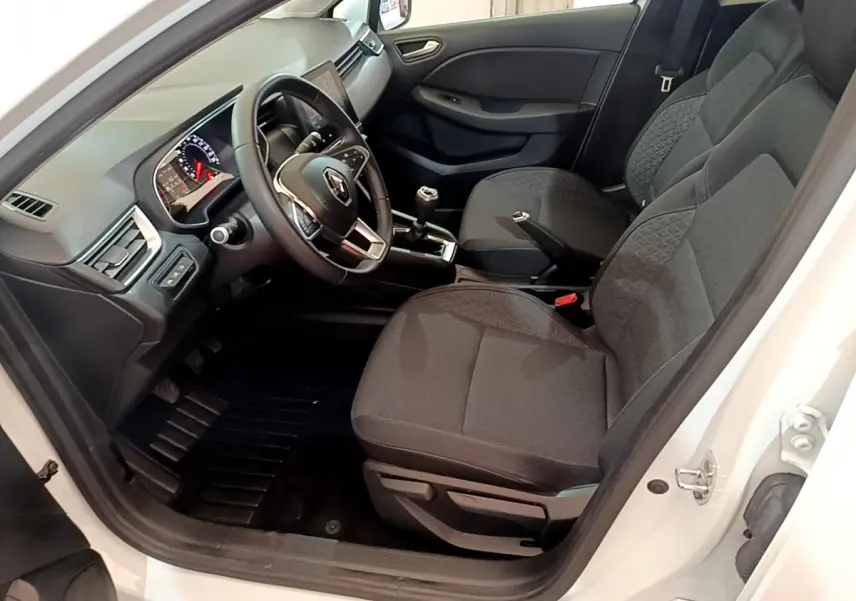 Intérieur côté conducteur de la Renault Clio Business blanche, montrant sièges noirs et tableau de bord avec écran tactile.