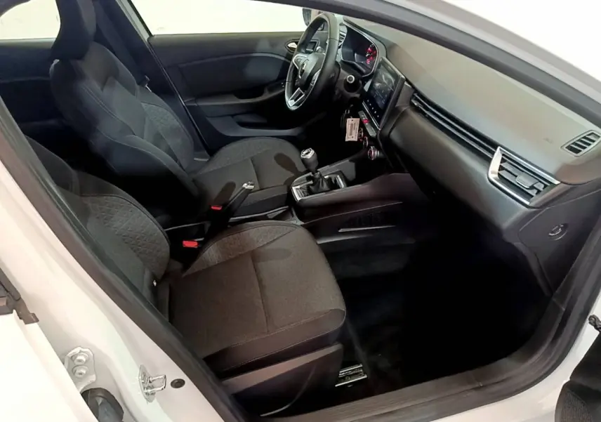 Intérieur côté conducteur d'une Renault Clio Business blanche, montrant sièges noirs et tableau de bord avec écran tactile.