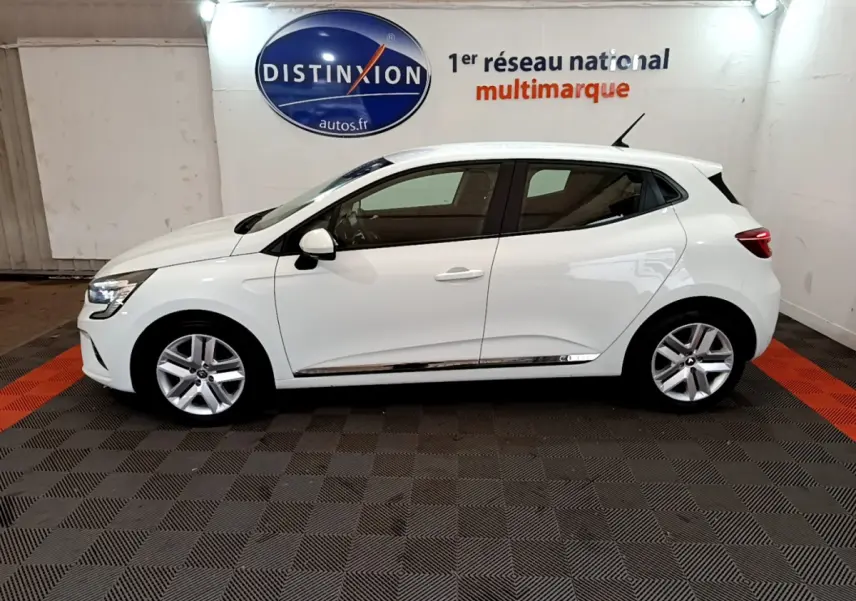 Profil droit d'une Renault Clio Business blanche 2021, avec jantes alliage et vitres teintées, en intérieur showroom.