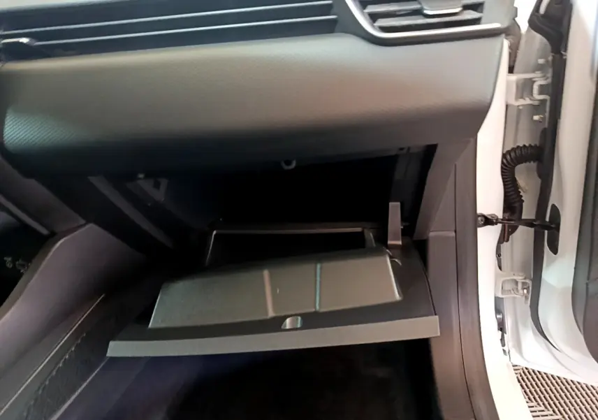 Vue rapprochée de la boîte à gants ouverte côté passager d'une Renault Clio Business blanche, intérieur noir.