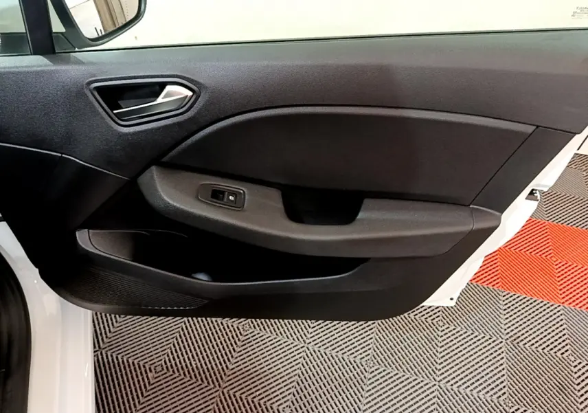 Vue intérieure sur la porte avant gauche noire d'une Renault Clio Business blanche, avec poignée et commande de fenêtre.