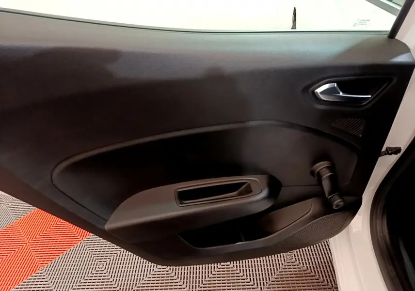 Vue intérieure de la porte côté droit noire d'une Renault Clio Business blanche avec manivelle de vitre visible.