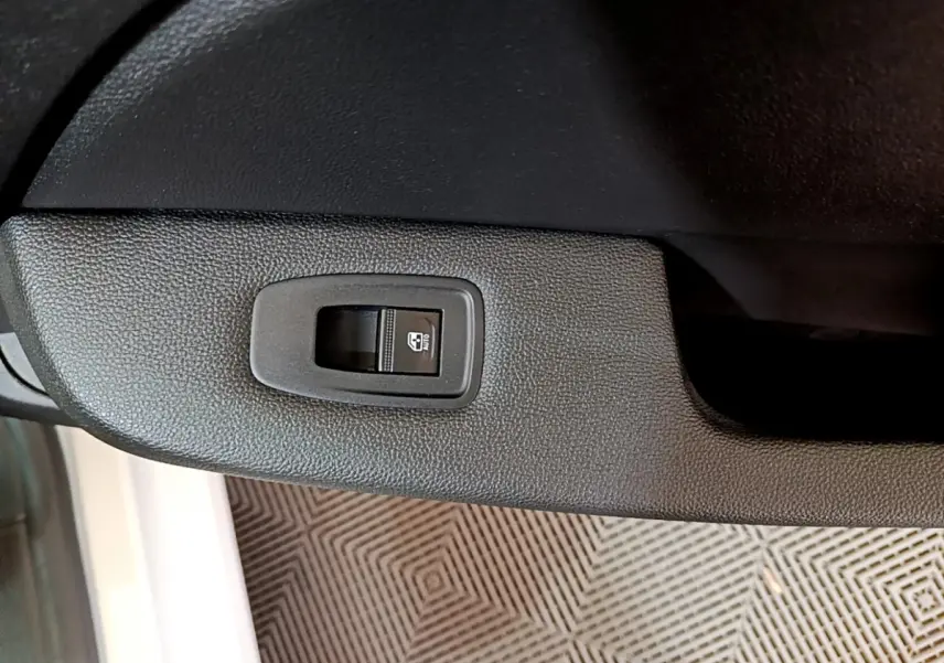 Bouton de commande de lève-vitre électrique côté conducteur sur portière noire d'une Renault Clio Business blanche 2021.