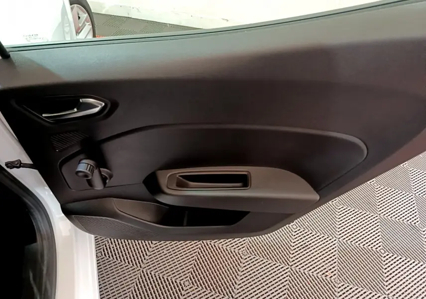 Vue intérieure de la porte côté gauche d'une Renault Clio Business blanche, avec poignée et commande manuelle de vitre.