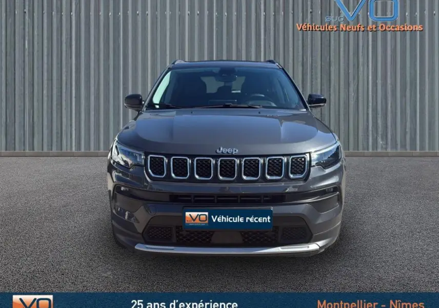 Vue frontale d'un Jeep Compass gris 2023 avec calandre à sept fentes et phares LED allumés.
