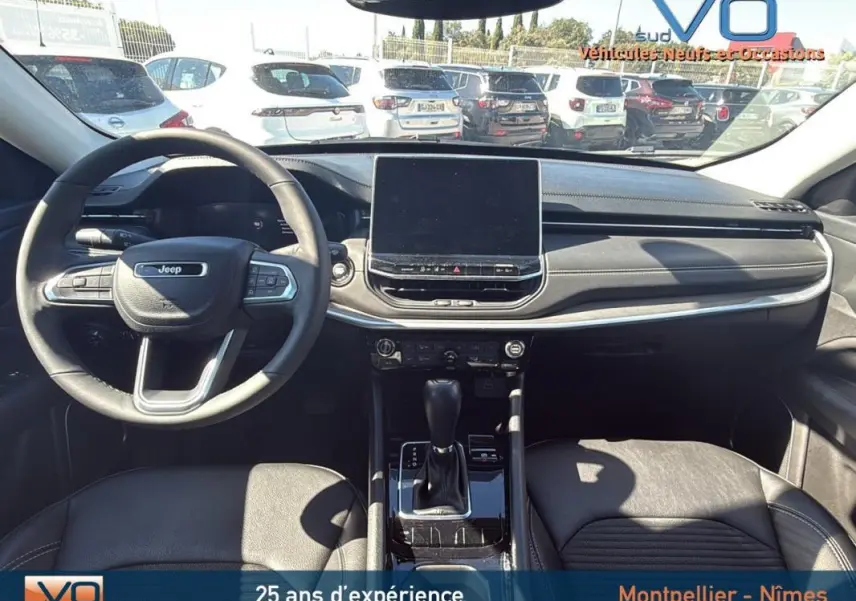 Intérieur du Jeep Compass gris 2023, vue frontale du tableau de bord avec écran tactile et volant multifonction.