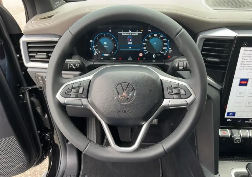 Vue rapprochée du volant cuir multifonctions et du tableau de bord digital du Volkswagen Amarok noir 2025.