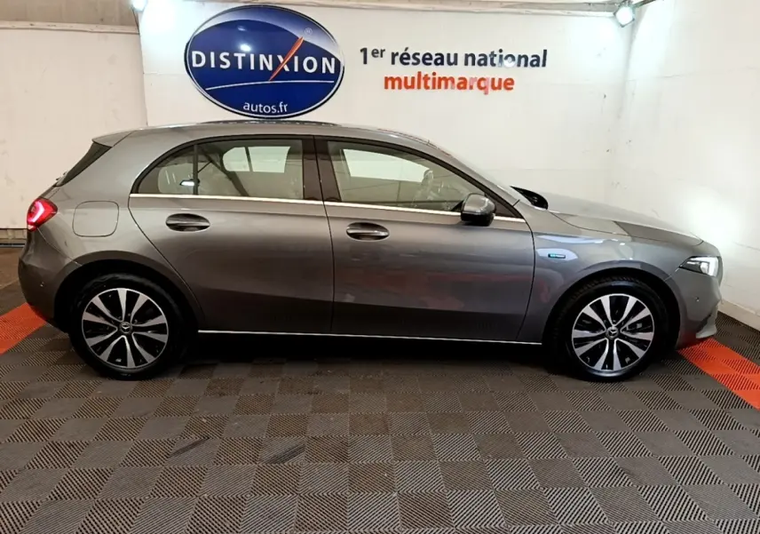 Vue latérale droite d'une Mercedes Classe A 250 e Business Line grise en hybride rechargeable dans un showroom.