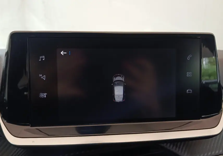 Écran tactile central affichant la vue aérienne de la Peugeot 208 PureTech 100 blanche, intérieur moderne.